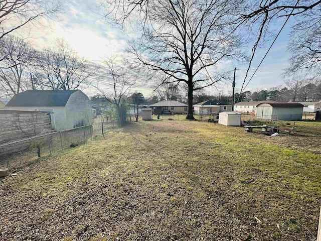 view of yard with fence, a storage unit, and an outdoor structure