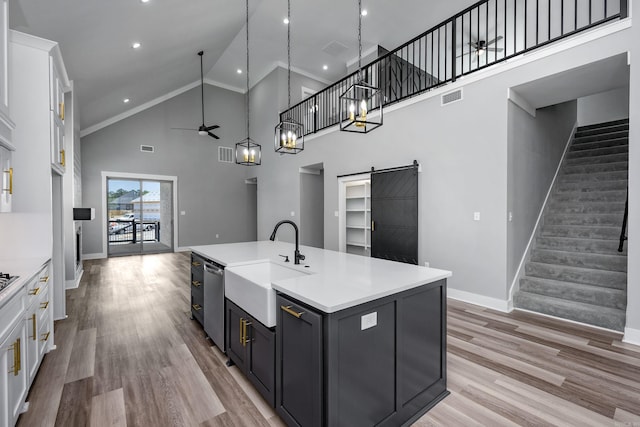 kitchen with a barn door, visible vents, white cabinets, dishwasher, and light wood-style floors