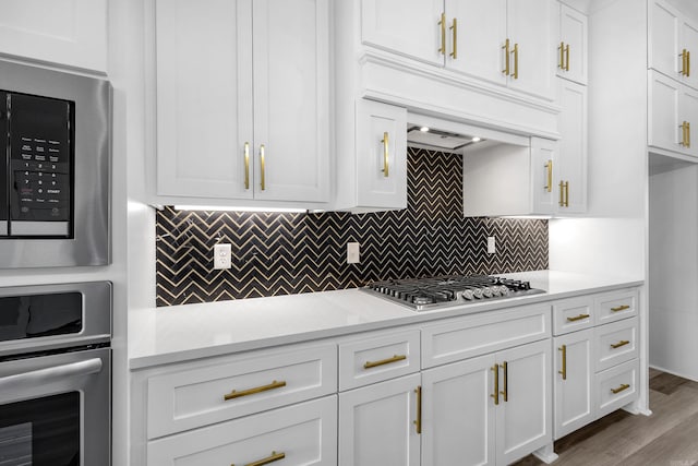 kitchen with light countertops, appliances with stainless steel finishes, white cabinetry, and tasteful backsplash