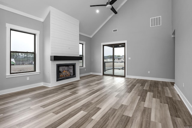 unfurnished living room with a large fireplace, visible vents, baseboards, and wood finished floors