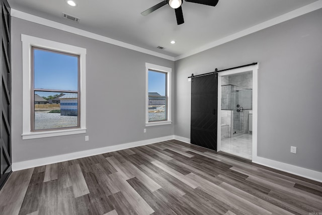 unfurnished bedroom featuring a barn door, multiple windows, visible vents, and baseboards