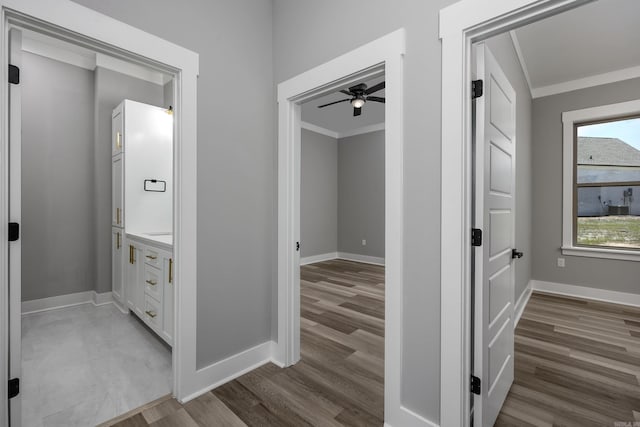 hall with crown molding, baseboards, and wood finished floors