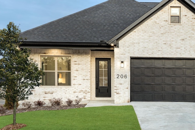 view of front of home with a garage, brick siding, concrete driveway, roof with shingles, and a front yard