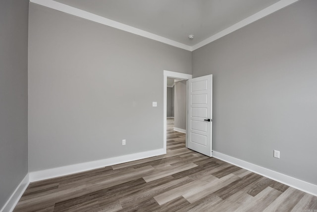 unfurnished room featuring ornamental molding, baseboards, and wood finished floors