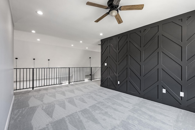 unfurnished room with recessed lighting, a decorative wall, a ceiling fan, and light colored carpet