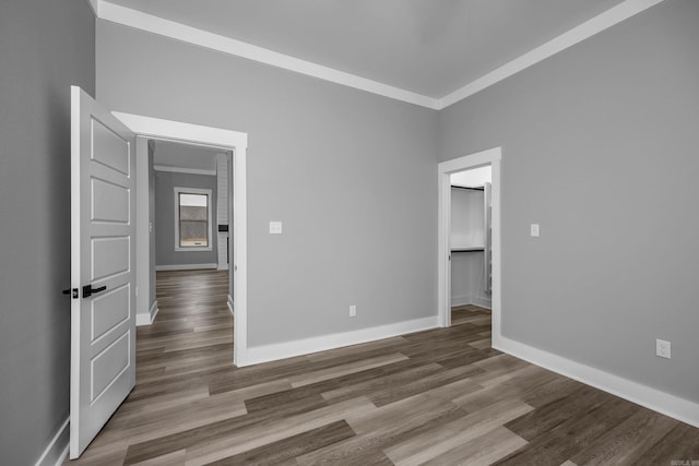 empty room with crown molding, baseboards, and wood finished floors