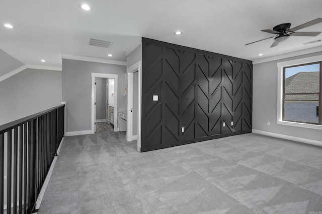 spare room with an accent wall, visible vents, and light colored carpet