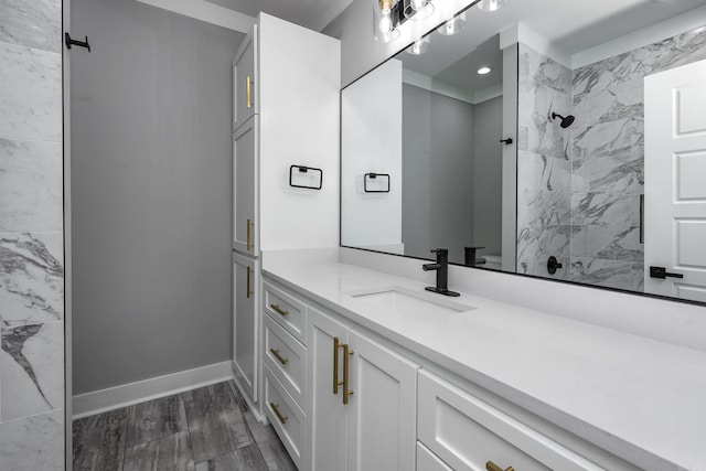 bathroom with recessed lighting, baseboards, a tile shower, and vanity