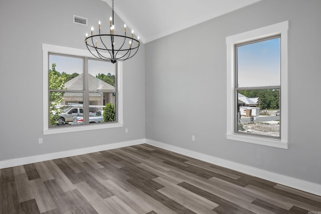 spare room with lofted ceiling, a notable chandelier, wood finished floors, visible vents, and baseboards