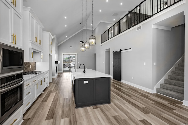 kitchen featuring light wood finished floors, a barn door, white cabinetry, and stainless steel appliances