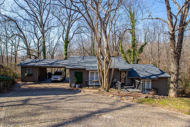 view of front of home with an attached carport and gravel driveway