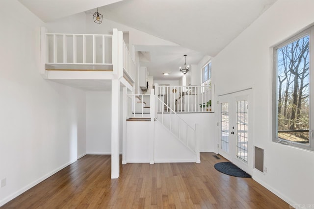 entrance foyer with wood finished floors, visible vents, baseboards, stairway, and an inviting chandelier