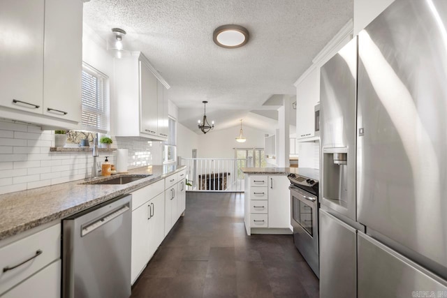 kitchen with backsplash, appliances with stainless steel finishes, white cabinets, a sink, and a peninsula