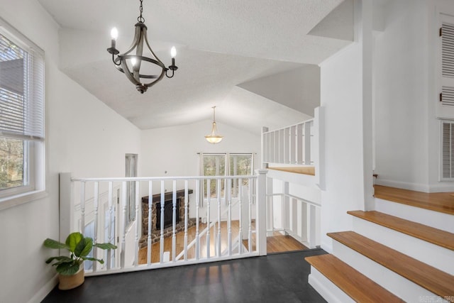 hall with lofted ceiling, a notable chandelier, a textured ceiling, and wood finished floors