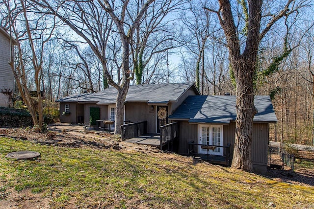 exterior space with a deck, french doors, and a front lawn