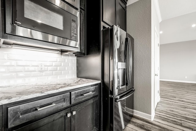 kitchen featuring built in microwave, baseboards, stainless steel fridge with ice dispenser, and wood finished floors