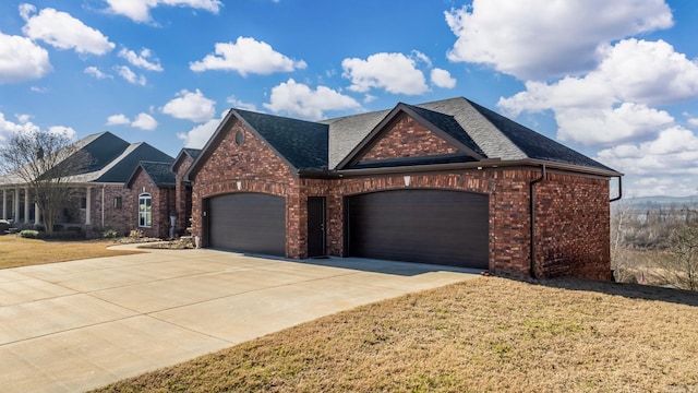 view of front of home with brick siding, roof with shingles, a garage, driveway, and a front lawn