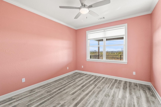 unfurnished room with ceiling fan, wood finished floors, visible vents, baseboards, and crown molding