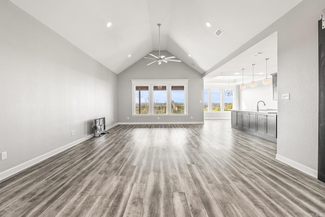 unfurnished living room featuring baseboards, visible vents, lofted ceiling, wood finished floors, and a sink