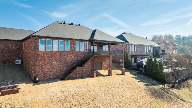 exterior space with brick siding, stairway, and roof with shingles