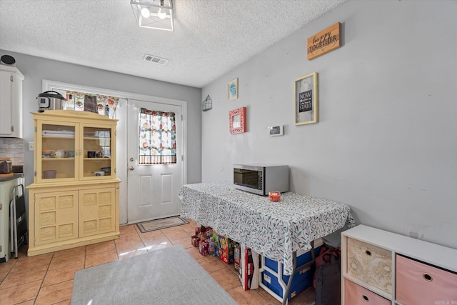 dining space with light tile patterned flooring, visible vents, and a textured ceiling