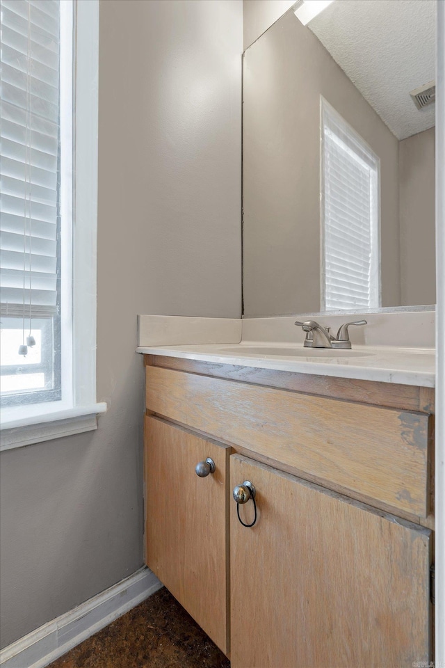 bathroom featuring visible vents, vanity, baseboards, and a textured ceiling