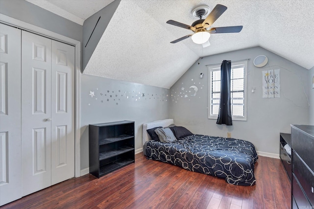 bedroom with lofted ceiling, a closet, hardwood / wood-style floors, a textured ceiling, and baseboards