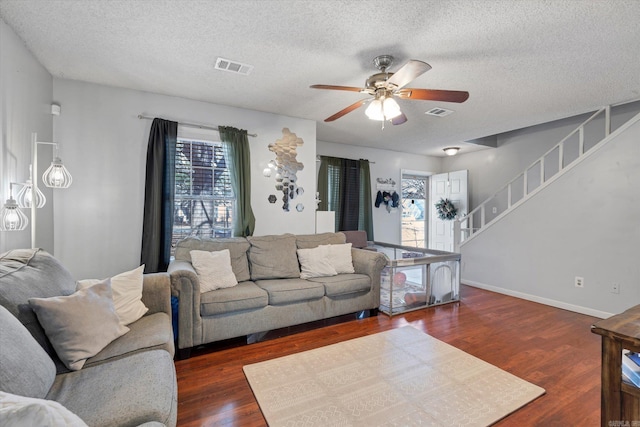 living area with wood finished floors, visible vents, baseboards, stairs, and a ceiling fan