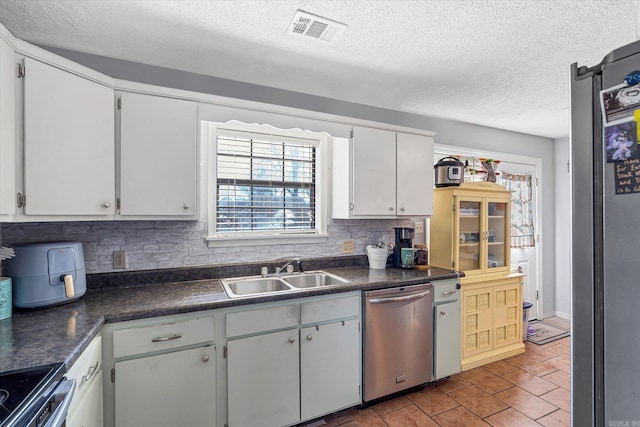 kitchen featuring a sink, visible vents, appliances with stainless steel finishes, tasteful backsplash, and dark countertops