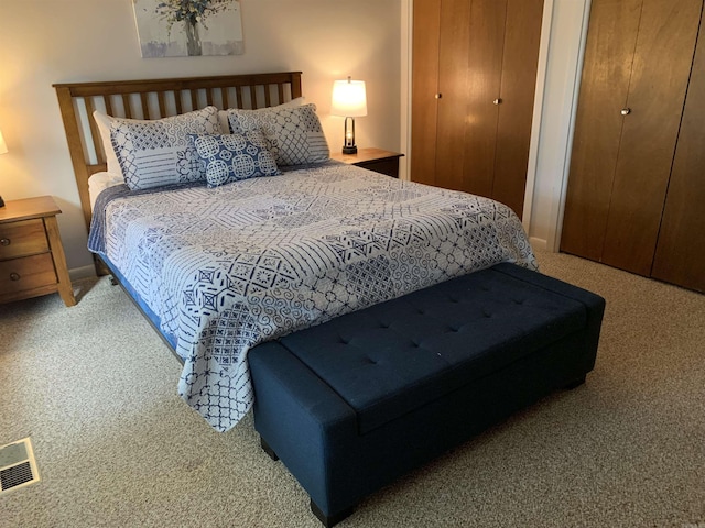 bedroom featuring two closets, visible vents, and carpet flooring