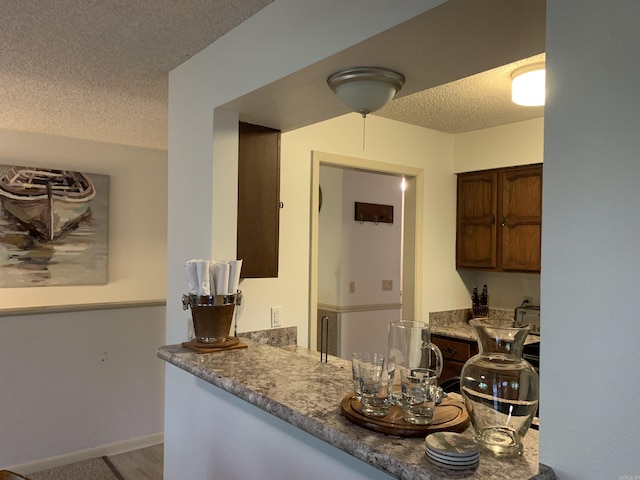 kitchen with a textured ceiling, baseboards, and wood finished floors