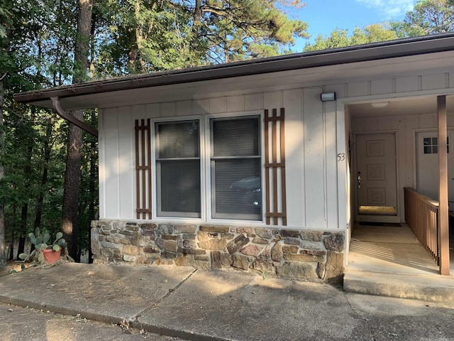 doorway to property featuring board and batten siding and stone siding