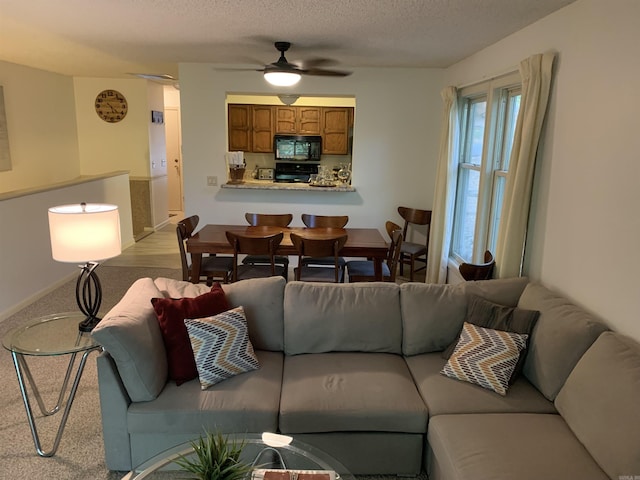 carpeted living area featuring a ceiling fan and a textured ceiling