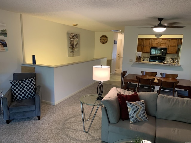 living room with a textured ceiling, carpet flooring, a ceiling fan, and baseboards