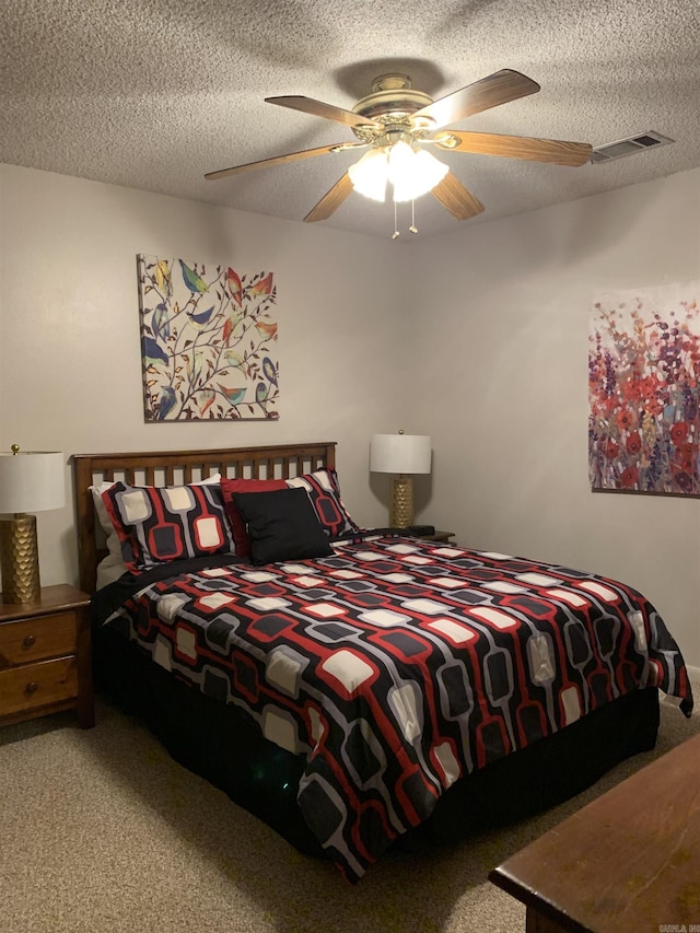 bedroom with a ceiling fan, carpet, visible vents, and a textured ceiling