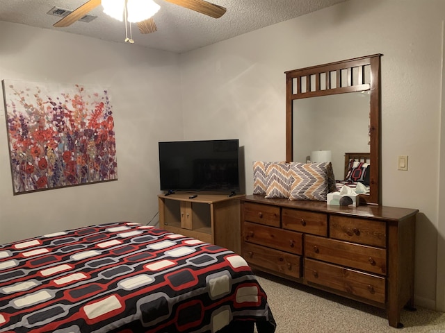 bedroom featuring ceiling fan, visible vents, a textured ceiling, and light colored carpet