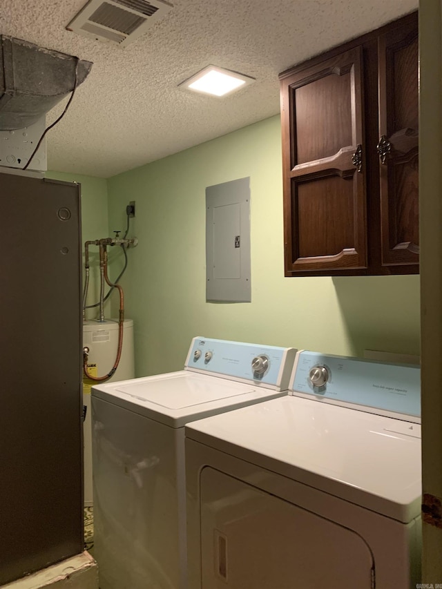 washroom featuring cabinet space, electric panel, visible vents, washing machine and clothes dryer, and a textured ceiling