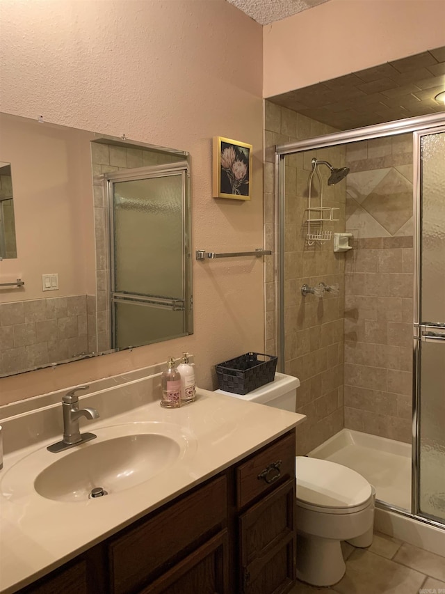 full bathroom featuring toilet, tile patterned floors, a textured ceiling, vanity, and a shower stall