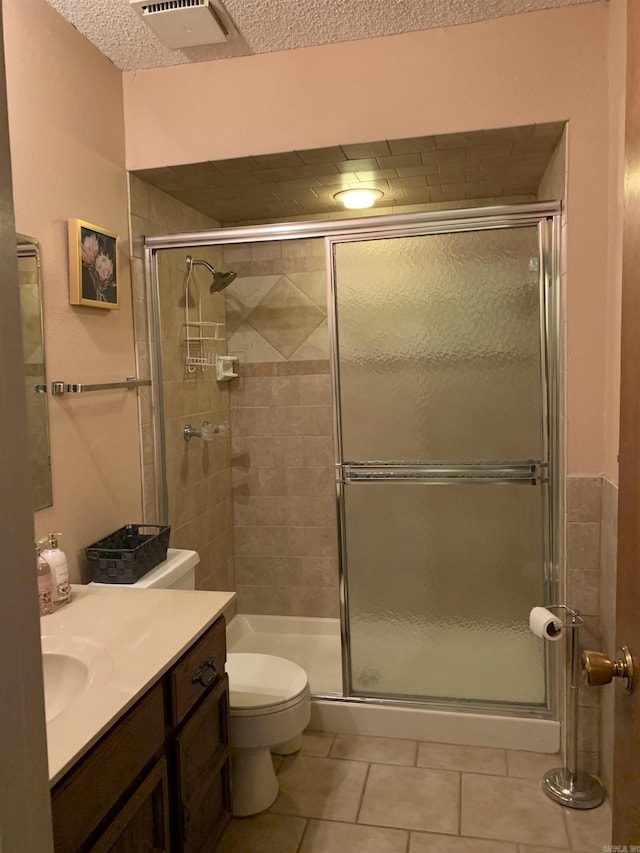 full bath featuring tile patterned flooring, toilet, vanity, visible vents, and a stall shower