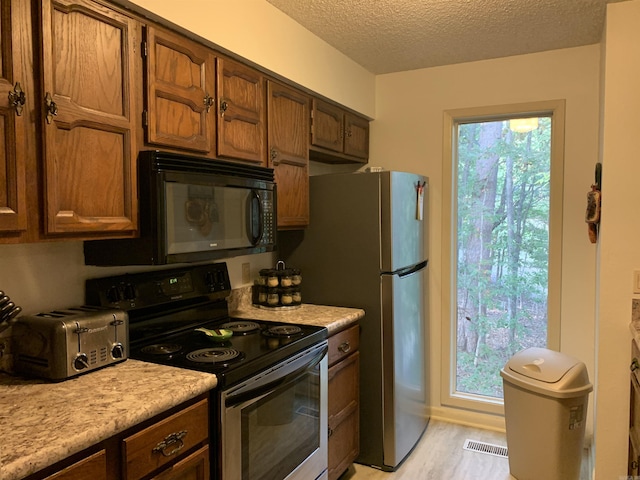 kitchen featuring black microwave, a textured ceiling, visible vents, light countertops, and stainless steel electric range