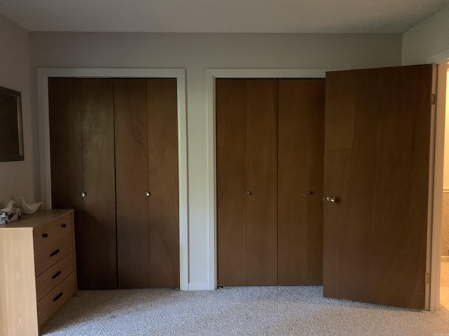 unfurnished bedroom with light carpet and multiple closets