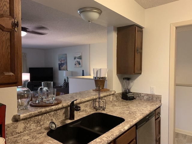 kitchen with a textured ceiling, stainless steel dishwasher, and a sink