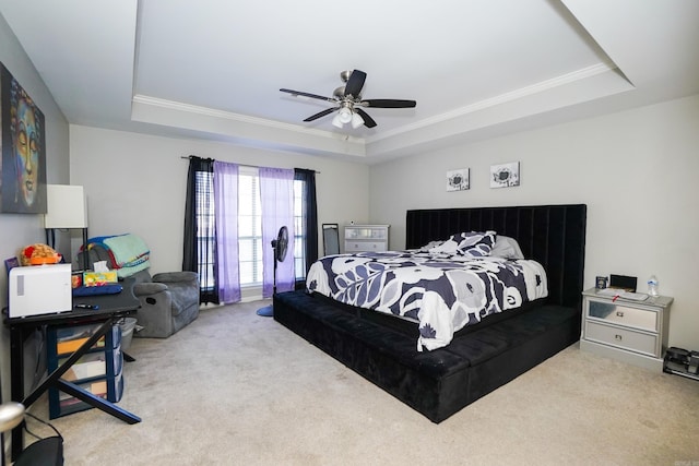 carpeted bedroom featuring a tray ceiling, crown molding, and ceiling fan