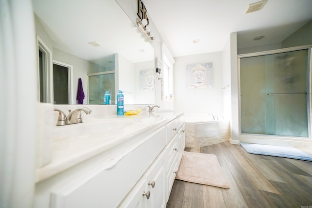 full bathroom featuring a stall shower, visible vents, a bath, wood finished floors, and a sink