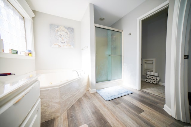 bathroom with a tub with jets, wood finished floors, a shower stall, and baseboards