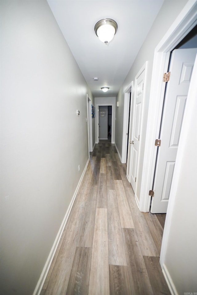 corridor with baseboards and wood finished floors