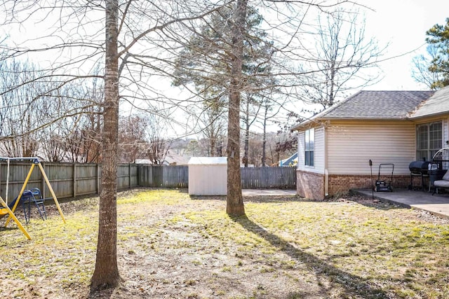 view of yard featuring a playground, an outdoor structure, a fenced backyard, and a patio