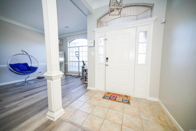 entryway featuring baseboards, light wood-type flooring, decorative columns, and crown molding