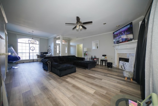 living area featuring ornamental molding, a tile fireplace, visible vents, and light wood finished floors