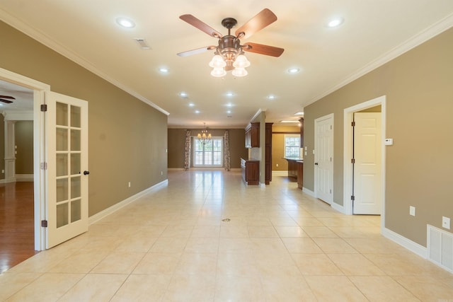spare room featuring ceiling fan with notable chandelier, ornamental molding, visible vents, and baseboards